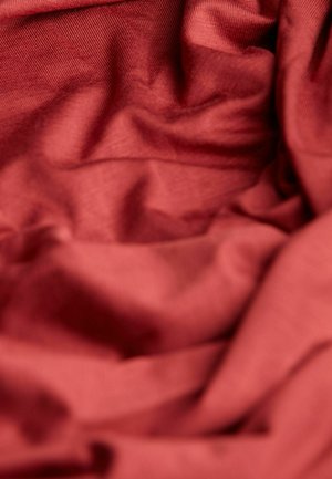 Strukturierten Stoff in tiefem Rot mit weichen, zerknitterten Falten und einer glatten Oberfläche, die Licht- und Schattenvariationen zeigt.