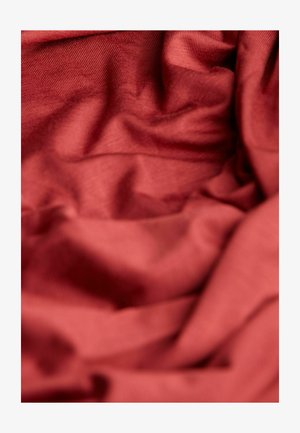 Tissu texturé en rouge profond, présentant des plis doux et froissés ainsi qu'une finition lisse, mettant en valeur les variations de lumière et d'ombre.