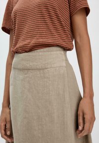 Braun- und rosa gestreiftes Kurzarmhemd kombiniert mit einem beigen Leinenrock, der eine glatte Textur und einen hohen Taillenbund aufweist.