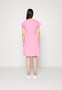 Vestido curto rosa com mangas soltas, cintura marcada e saia em camadas. Feito de tecido suave, tem um ajuste simples e descontraído.