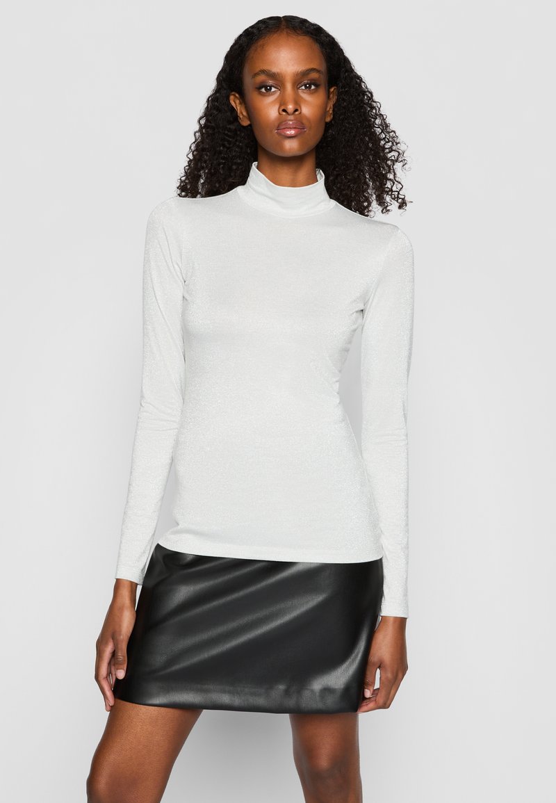 Langärmliges Turtleneck-Oberteil aus schimmerndem weißen Stoff, kombiniert mit einem engen, schwarzen Fake-Leder-Minirock. Glatte Textur, elegantes Design.