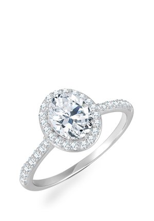 Ovaalse lõikega teemant sõrmus, mille on seadnud poleeritud valge metall, ümbritsetud väiksemate teemantide halo'ga bändi ümber, et lisada sära.