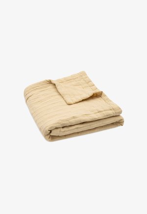 Opgevouwen beige gewatteerde deken met een gestructureerd, gestikt patroon, een hoekje licht omgeslagen waardoor de dikte van de stof zichtbaar is.