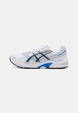 Scarpe sportive bianche realizzate in mesh e materiali sintetici, caratterizzate da accenti neri e blu, una suola ammortizzata e un design con lacci.