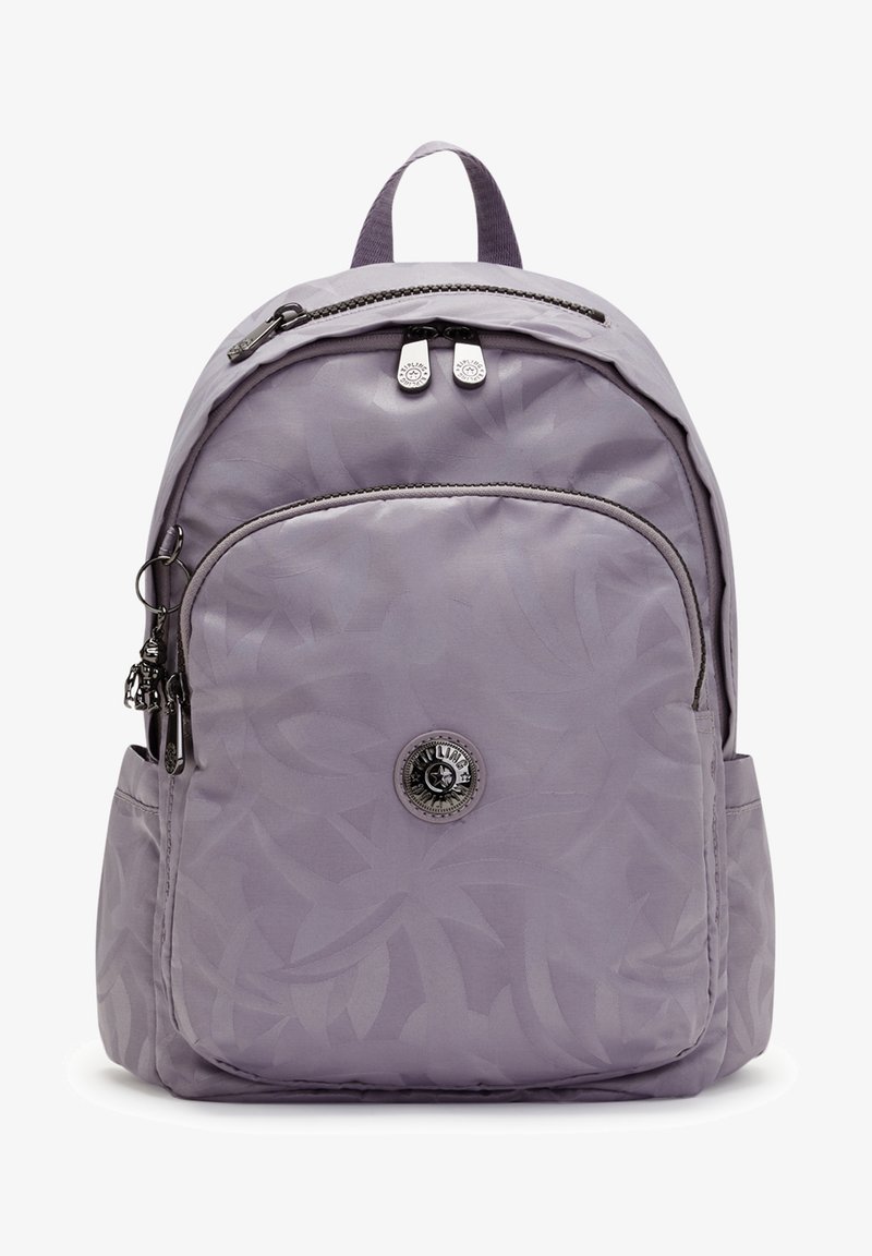 Mochila de color lila claro con un sutil patrón de hojas, cierre de doble cremallera, bolsillo frontal y un detalle de logo circular en el centro.