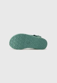 Teva sandal sole in light teal with a textured design featuring hexagonal patterns for traction. Reinforced edges and branding visible.