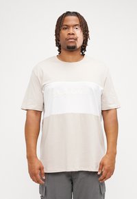 Beige en witte t-shirt met korte mouwen en een rechte snit, voorzien van een reliëflogo op de borst. Gladde katoenstof.