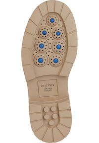 Beige gummisula på sko med cirkulära ventilationshål och blå accenter. Texturerat mönster och Geox-märke vid hälen.