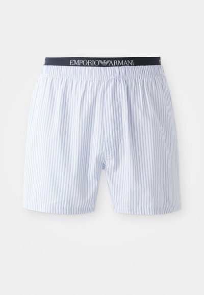 Μπλε και λευκές ριγέ σλιπ με ελαστική ζώνη που διαθέτει μαύρο λογότυπο "Emporio Armani". Κατασκευή από βαμβάκι, άνετη εφαρμογή και χωρίς φερμουάρ.