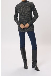 Bluzka z długim rękawem i wysokim kołnierzem w kolorze granatowym z kwiatowym wzorem, zestawiona z ciemnoniebieskimi rurkami i czarnymi skórzanymi kozakami za kolano.