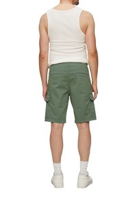 Groene cargoshorts met zijzakken, gemaakt van lichtgewicht stof, gecombineerd met een witte tanktop en witte sneakers. Achteraanzicht getoond.