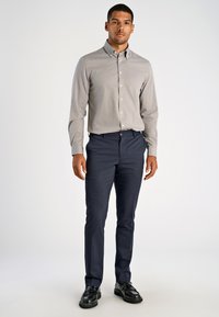 Grijs gemarmerd hemd met lange mouwen, gecombineerd met donkerblauwe broek en zwarte nette schoenen. De outfit is netjes gestreken.