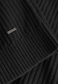 Schwarzer gestrickter Pullover mit gerippter Struktur, versehen mit einem kleinen metallischen Logotag. Der Stoff zeigt feine Details und eine mittlere Dicke.