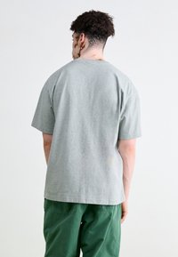 Graues Baumwoll-T-Shirt mit kurzen Ärmeln, lässiger Passform, rundem Ausschnitt und glatter Textur. Hervorhebenswert ist das schlichte Design und das Fehlen von Grafiken.