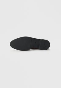 Black leather dress shoe sole with slight texture and a small "BOSS" logo near the heel on a white background.