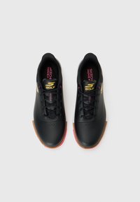 Black golf shoes with a smooth synthetic upper, rubber sole, pink accents, and gold logo. Features traditional lacing and rounded toe design.
