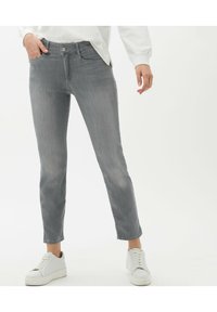 Šedé slim-fit džíny z denimu, s předním zapínáním na knoflík, bočními kapsami a jemným oděrem. Vzájemně sladěné s bílými teniskami.