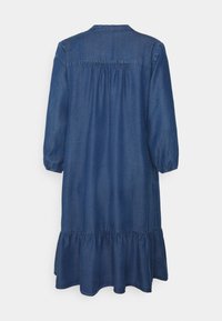 Vestido de mezclilla en azul oscuro, a la altura de la rodilla, con mangas de tres cuartos y una espalda fruncida. El dobladillo es conVolantado, añadiendo textura al diseño.