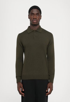 Olijfgroene polo trui met lange mouwen, een gestructureerde brei, klassieke kraag en geribde manchetten, gedragen met zwarte broek tegen een effen achtergrond.