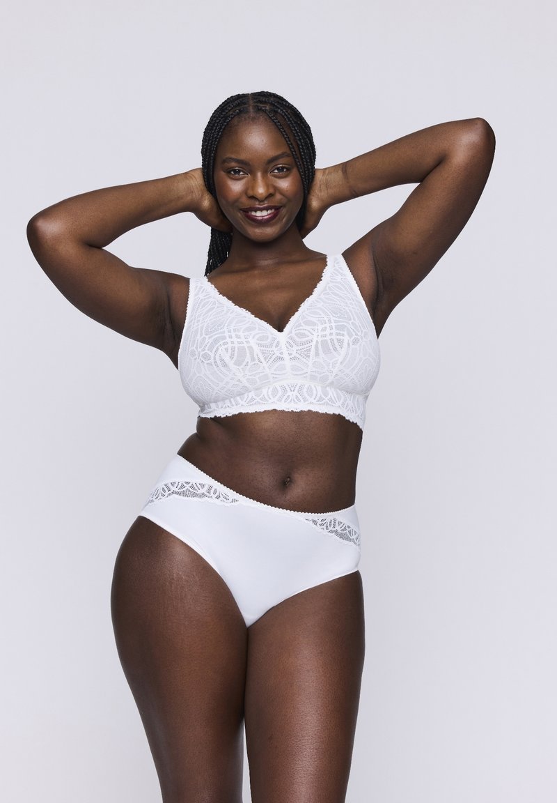 Bralette bianco in pizzo e bikini a vita alta, caratterizzati da delicate fantasie e bordi ondulati, che mettono in risalto il tessuto morbido e un design aderente.