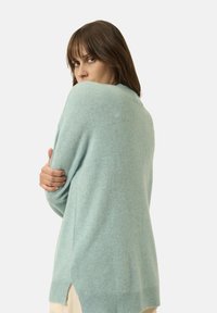 Hellblaues Cashmere-Sweatshirt mit lockerer Passform, langen Ärmeln, seitlichen Schlitzen und geripptem Saum. Weiche Textur und minimalistische Designdetails.