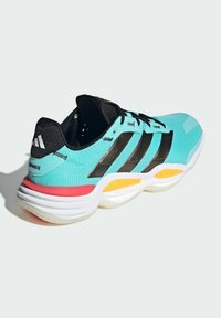 Aqua- und schwarze Sportschuh mit drei schwarzen Streifen, strukturiertem Mesh-Obermaterial und lebhaften roten sowie gelben Akzenten auf einer weißen Sohle.