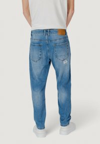 Jeans de mezclilla azul claro con un corte relajado, que cuentan con dos bolsillos traseros, una parche de cuero en la cintura y sutiles detalles desgastados.