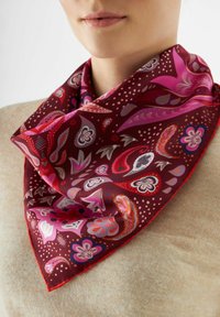 Zijde sjaal in donkerrood met roze paisley- en bloemmotieven, met een driehoekige vorm en afgewerkte randen, gedragen om de nek.