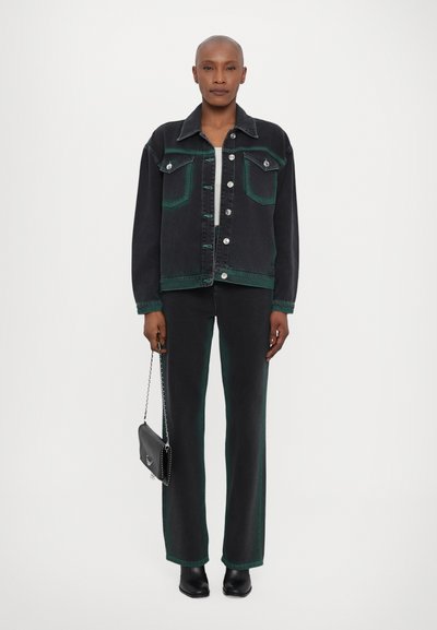 Veste en denim noir avec des accents verts, boutons en argent et poches poitrine doubles, associée à un pantalon noir assorti. Texture lisse, coupe droite.