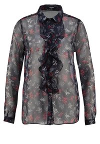 Blusa trasparente blu navy con motivo floreale in rosso e bianco. Presenta una ruffle plissettata sul davanti e maniche lunghe con polsini a bottone.