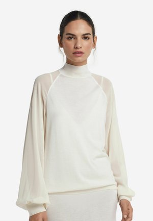 Vit top med hög hals och genomskinliga långa ärmar, med en avslappnad passform och mjukt material, som framhäver en minimalistisk design med diskreta detaljer.