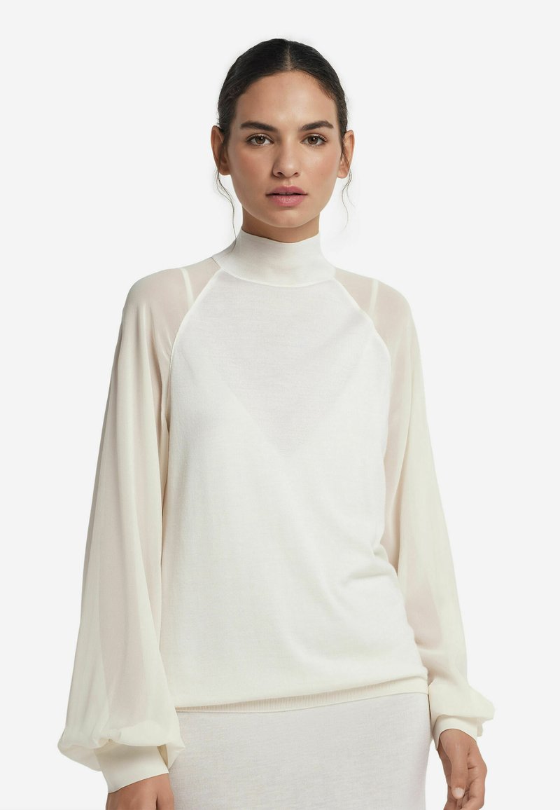 Top bianco a collo alto con maniche lunghe trasparenti, caratterizzato da una vestibilità rilassata e una consistenza morbida, che mette in risalto un design minimalista con dettagli sottili.