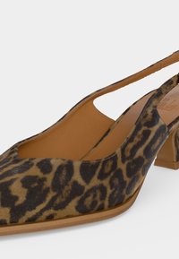 Γυναικείο slingback παπούτσι με μεσαίο τακούνι, μυτερή μύτη, επάνω μέρος με σχέδιο λεοπάρδαλης, ταμπά πάτο και χαμηλό τακούνι μπλοκ σε λευκό φόντο.