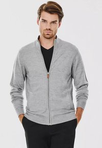 Szary cardigan na zamek błyskawiczny z kołnierzem stójkowym, ściągaczami przy mankietach i u dołu. Miękka tekstura; ma mały skórzany akcent na uchwycie zamka.