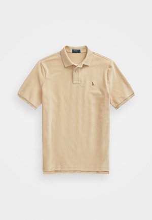 Polo beige à manches courtes avec col et deux boutons, petit logo brodé sur le côté gauche de la poitrine, posé à plat sur fond blanc.