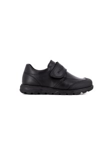 Zapato de cuero negro con punta redondeada, correa de velcro y suela texturizada para agarre. Presenta detalles de costura y un diseño de bajo perfil.