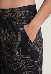 Marineblauwe broek met een bloemenpatroon in roomkleur, voorzien van een elastische tailleband en zijzakken, gemaakt van een soepele, lichte stof.