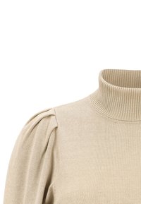 Pull beige avec un col montant côtelé, un tissu en maille texturée et des manches bouffantes douces, offrant une coupe décontractée au niveau des épaules.