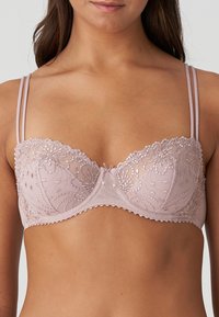 Jasnoróżowy biustonosz z koronką, zdobiony florystycznymi haftami, z przezroczystymi miseczkami, delikatnymi ramiączkami, falbaniastymi krawędziami i centralną kokardką.