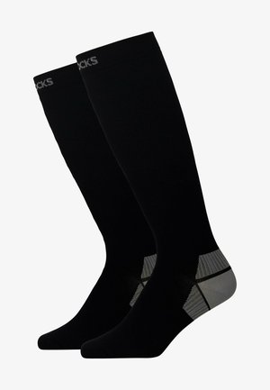 Zwarte kniehoge sokken met een geribbelde textuur, voorzien van een zilver- en grijsaccentontwerp bij de hiel en branding aan de bovenkant.