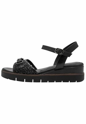 Schwarze Sandale mit offenem Zehenbereich, geflochtenem Vorderfußriemen, Knöchelriemen mit Schnalle und dicker Sohle mit profiliertem Boden für besseren Halt.