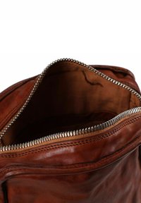 Borsa in pelle marrone con una texture liscia, dotata di una cerniera in metallo argentato e un bordo cucito lungo l'apertura, che mostra un interno in tessuto.