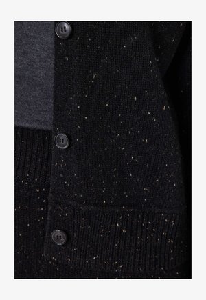 Cardigan nero a maglia con una finitura texture, caratterizzato da macchie bianche e bottoni neri lungo la parte anteriore. Polsini e orlo a costine.
