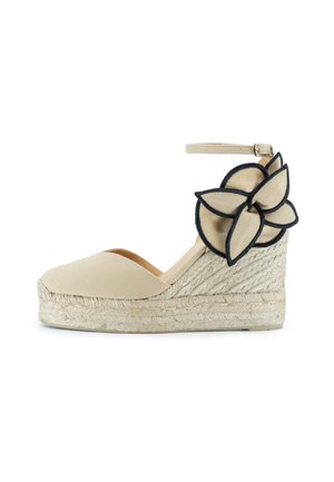 Scarpa con zeppa in tela beige con suola in juta intrecciata, caratterizzata da un accentuazione floreale nera e beige sul lato e una cinghia alla caviglia regolabile.
