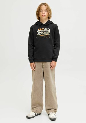 Un sweat à capuche noir avec le logo "JACK & JONES" en couleurs métalliques, associé à un pantalon large marron clair et des baskets noires et blanches.