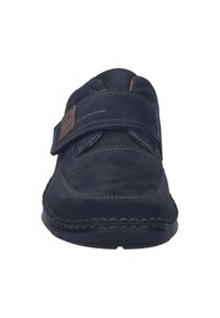 Scarpa in suede nera con una fascia in Velcro, tomaia texturizzata, cuciture rinforzate e suola in gomma, progettata per comfort e facilità di calzata.