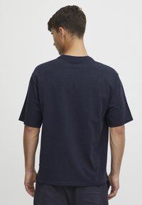 Marineblå bomulds t-shirt med korte ærmer og rund hals. Stoffet ser blødt ud, med en afslappet pasform og minimale designdetaljer.