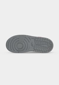 Σόλα ενός γκρι αθλητικού Nike με κυκλικά και ορθογώνια σχέδια πέλματος και το λογότυπο Nike ανάγλυφο στο κέντρο.
