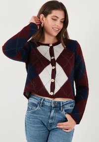 Red, navy, and white argyle-patterned cropped cardigan with gold buttons and long sleeves. Made of soft, textured knit material.