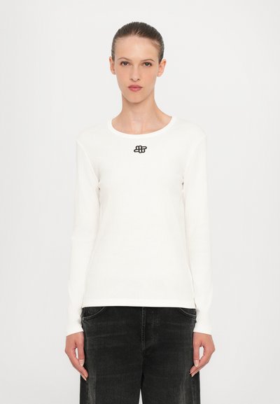 Camiseta de manga larga y de canalé blanca con un logo negro en el cuello. Fabricada con un tejido suave, tiene un cuello redondo y una silueta ajustada.